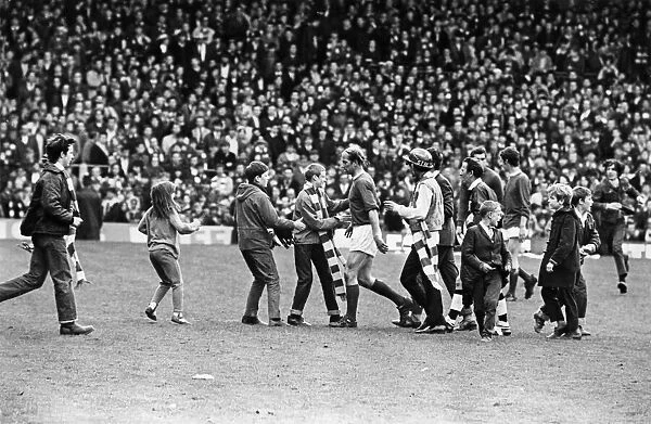 Bobby Charlton leaving the pitch at Old Trafford with young fans rushing to shake his