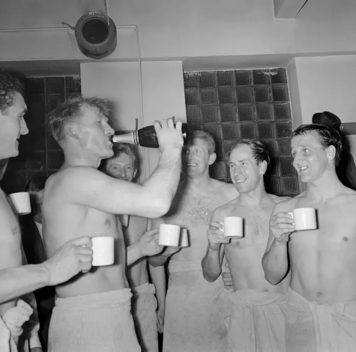 Framed Print : Bobby Charlton and others look on as Bert Trautmann drinks champagne from the bottle in Framed Print : Bobby Charlton and others look on as Bert Trautmann drinks champagne from the bottle in