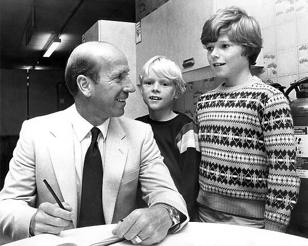 Bobby Charlton signs his autograph for David Laws (centre