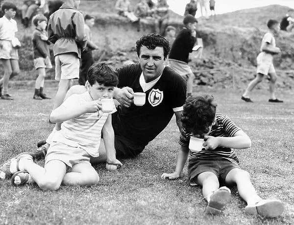 Bobby Smith of Tottenham Hotspur drinking a cup of tea with two young boys during a