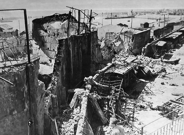 Bomb wrecked warehouses and freight wagons on the quayside at Catania