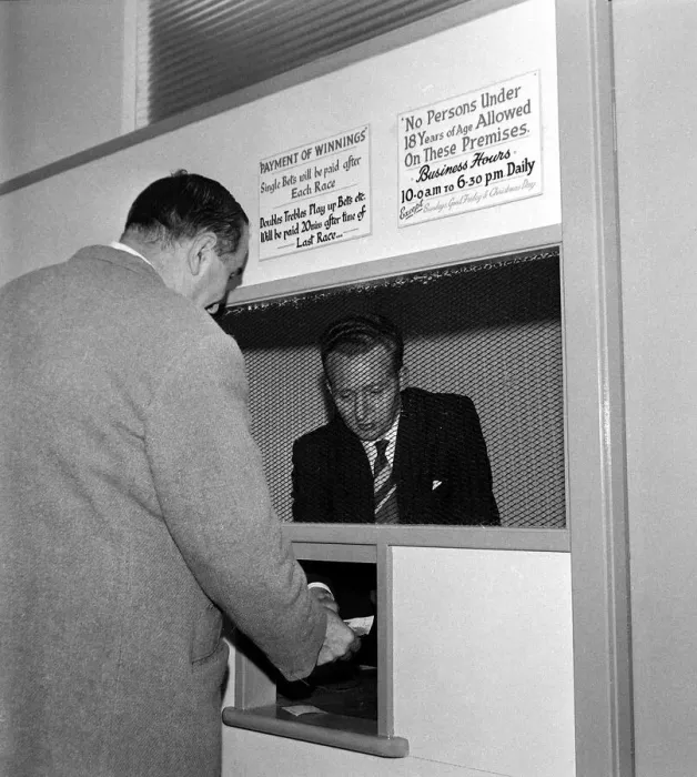 Framed Print : A bookmaker accepting a bet from a punter at Eric Barbers betting shop in Old Trafford Framed Print : A bookmaker accepting a bet from a punter at Eric Barbers betting shop in Old Trafford