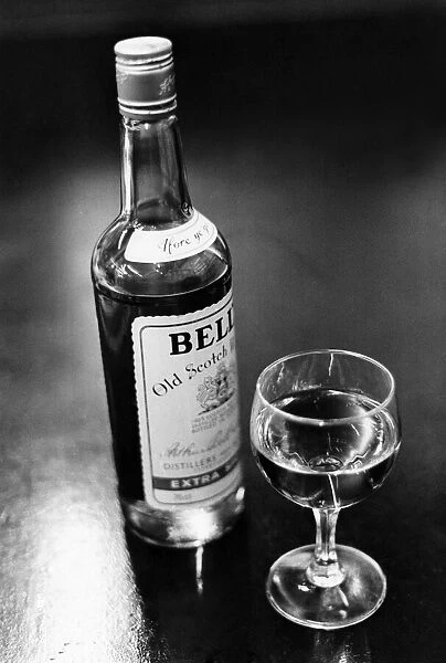A bottle of Bells whisky and a poured glass beside it. April 1983 P009582