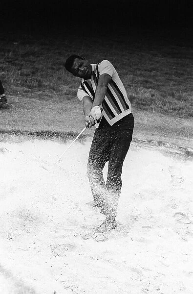 Boxer Sugar Ray Robinson relaxing with a game of golf trying to get the ball out of