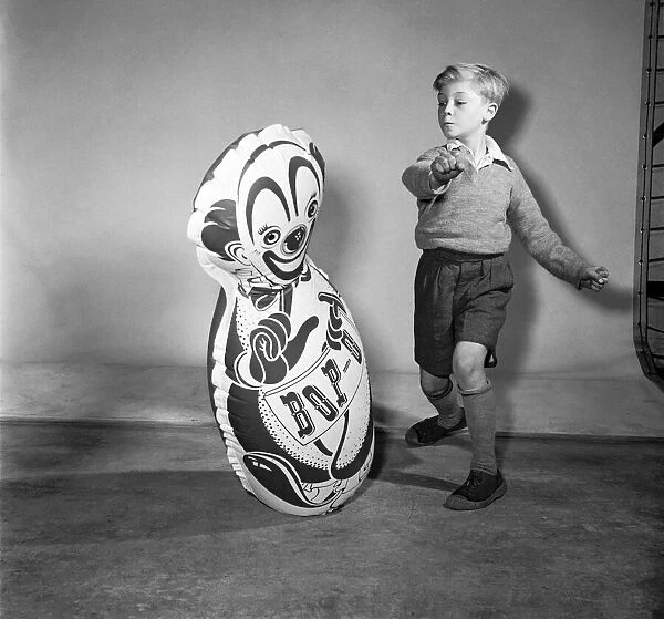 Boy boxing a toy punch bag. December 1953 D7218
