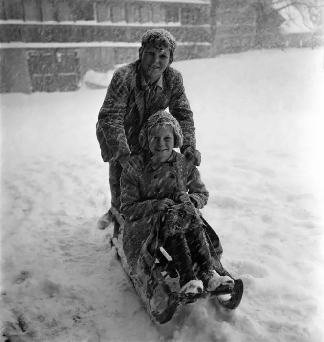 Framed Print : Boy and girl on a wooden sledge in the snow at a resort in Switzerland