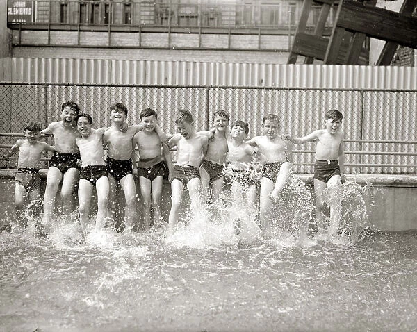 Boys kicking up water in swimming pool, summer 1951