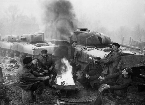 Boys of a tank recovery unit keeping warm in the wintry weather in Belgium. December 1944