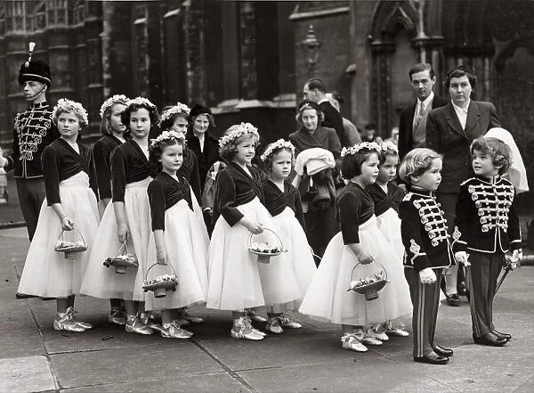 Two boys tressed as toy soldiers marshalling a long line of bridesmaids outside St