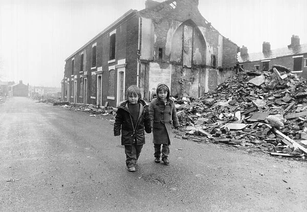 Two boys walk pass the partially demolished row of terrace houses in Blackburn May