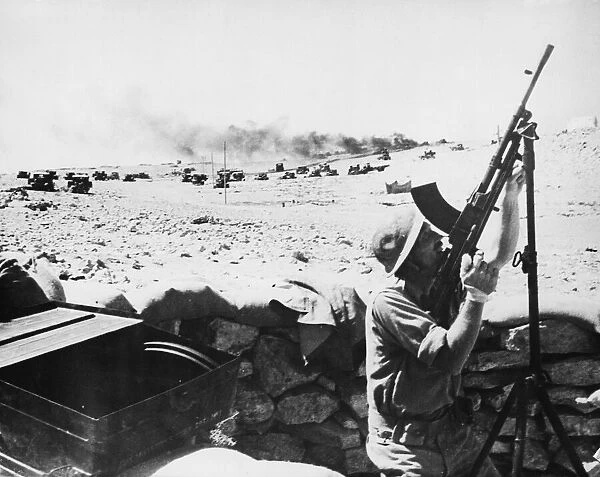 Bren gunner in action against bombers, in the background a lorry can be seen burning in
