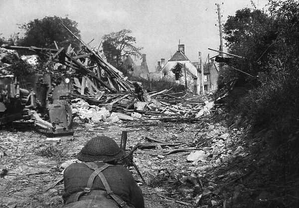 A Bren gunner takes up a position near wrecked houses on the roadway leading to