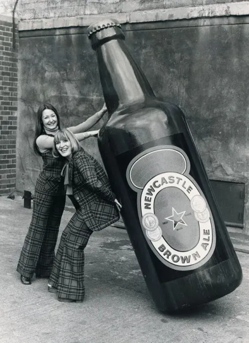 Framed Print : Brenda Kelly (without jacket) and Jennifer Donkin holding a nine foot tall bottle of Framed Print : Brenda Kelly (without jacket) and Jennifer Donkin holding a nine foot tall bottle of