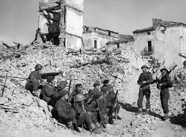 British army pipers of the 5th Army entertain their comrades in a heavily damaged village