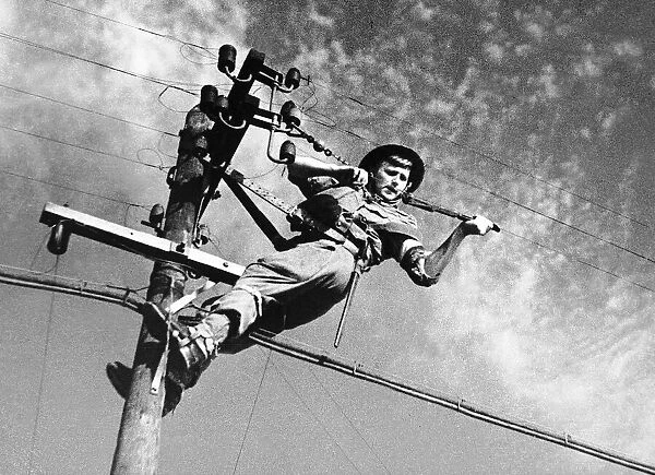 A British Army signalman at the top of a telegraph pole maintaining communication during
