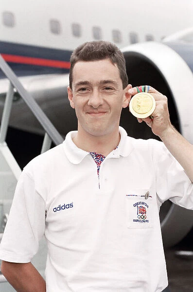 British cyclist Chris Boardman poses on arrival at Heathrow Airport as he returns home
