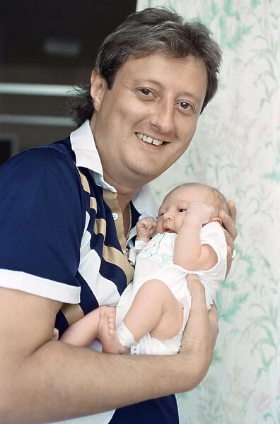 British darts player Eric Bristow poses at home with his new born baby girl who has been