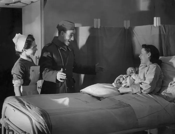 Framed Print : A British serviceman looks surprised as his wife presents him with a newborn baby Framed Print : A British serviceman looks surprised as his wife presents him with a newborn baby