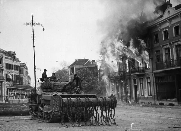 A British Sherman Crab flail tank moves up through the burning buildings in Arnhem