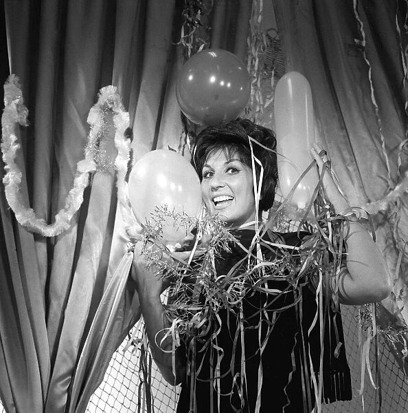 British singer Alma Cogan wraps herself in Christmas decorations at ATV House in Marble