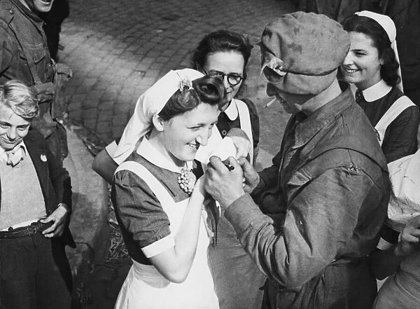 A British soldier autographs the cap of a Dutch nurse at Eindhoven as a souvenir of