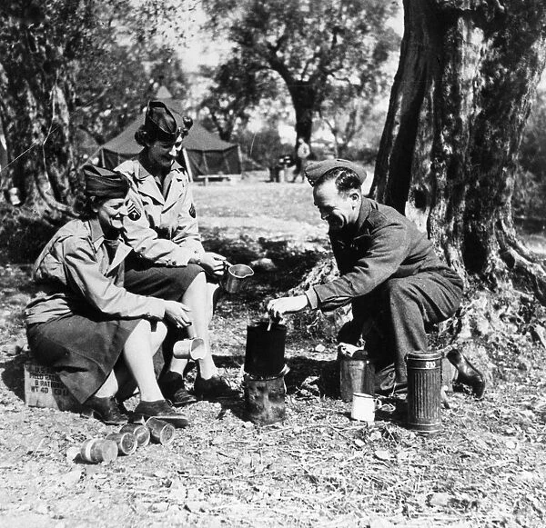 A British soldier enjoys a cup of tea with two women of the American Women