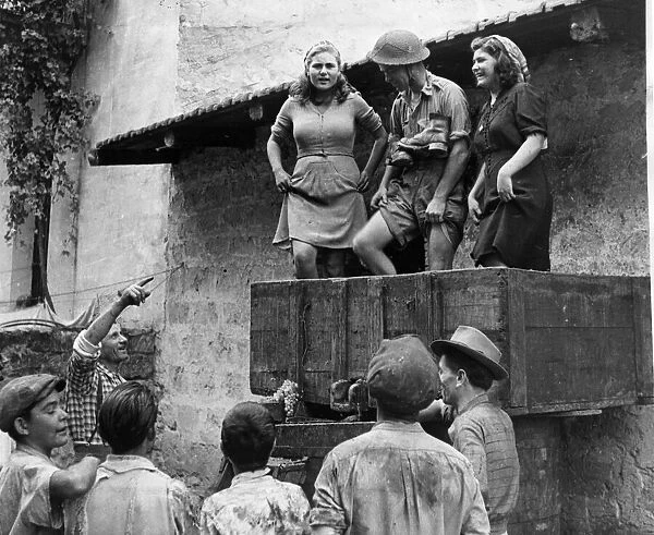 A British soldier helping the local villagers with the winepress after the Allied army