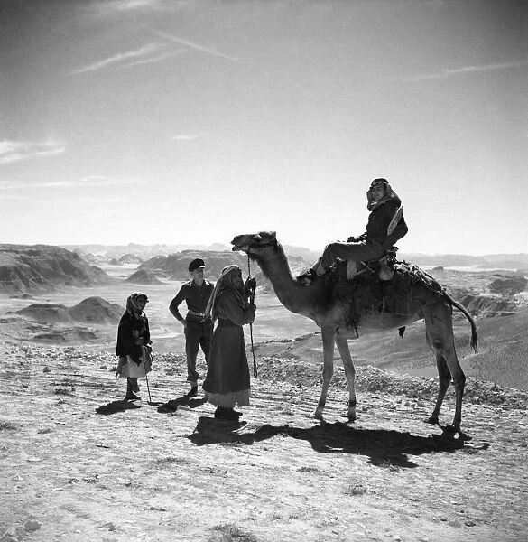 British soldiers with local Arab people and camel in the desert of Jordan