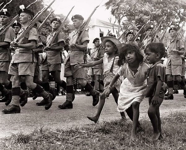 British soldiers marching in Georgetown British Guiana followed by some children in 1953