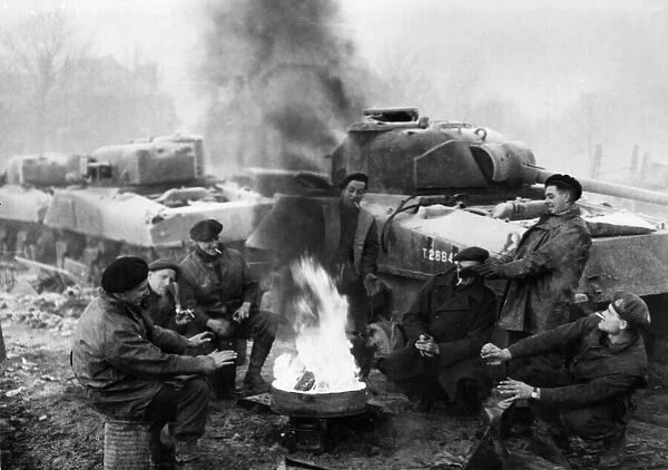 British soldiers of a tank recovery unit keep warm around a fire in the wintry weather