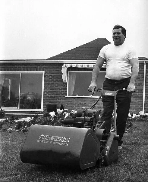 British wrestler Count Bartelli at the helm of a huge lawn mower on the lawn of his home