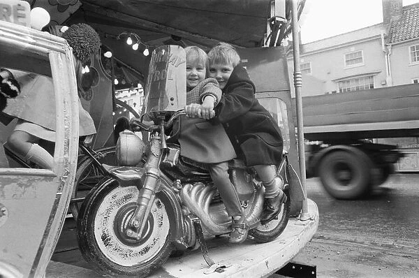 Brother and sister riding a motorcycle on a childs roundabout at the Northallerton