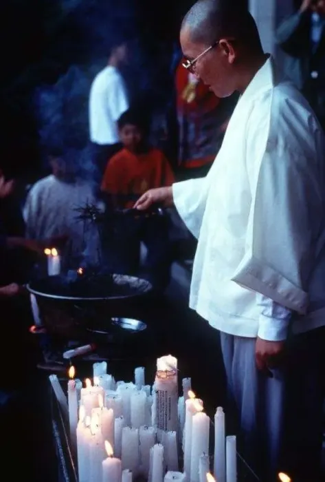  : Buddhist monk lighting candles at a Buddhist church service circa 1997