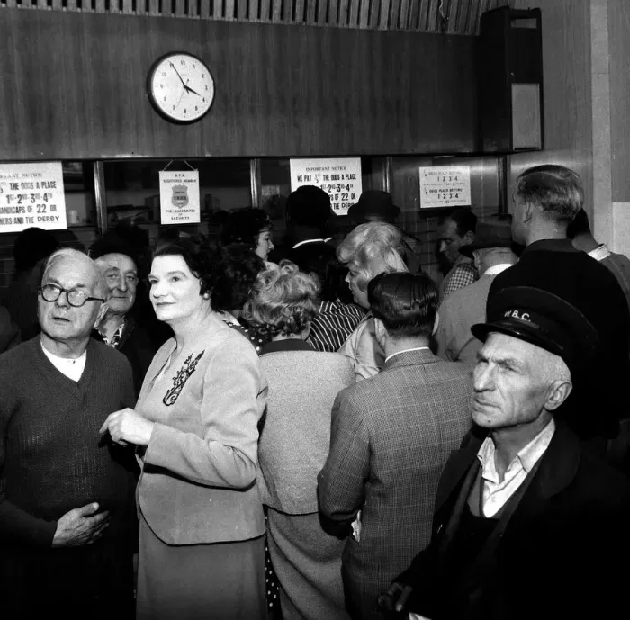 Framed Print : A busy scene inside a betting shop with punters queuing to make bets minutes before
