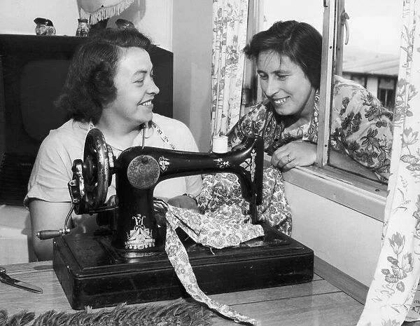 Busy at her sewing machine is Mrs. Beaty Evans, her next door neighbour, Mrs