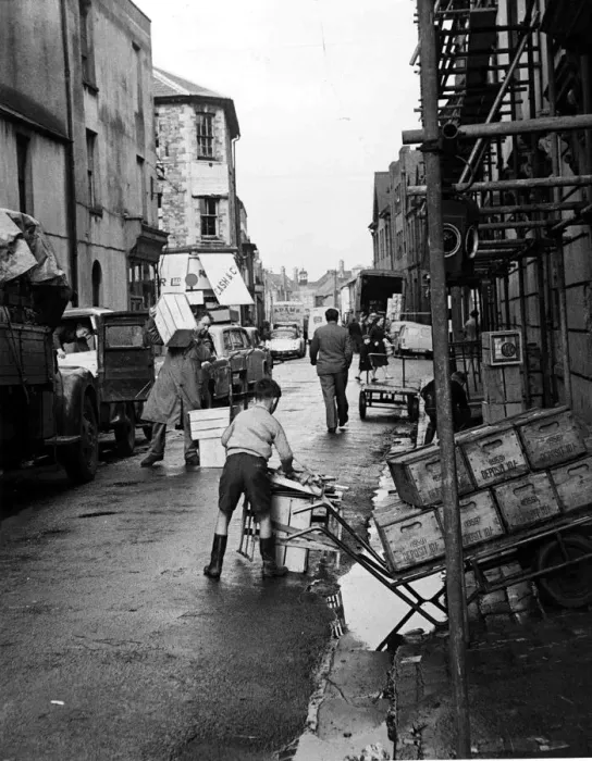 Framed Print : A busy street scene as traders, workmen and children go about their business