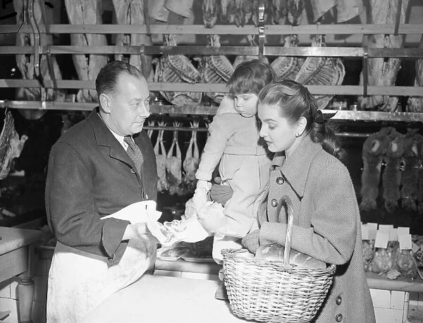 Butcher offers choice cuts of meat to a woman shopper March 1952