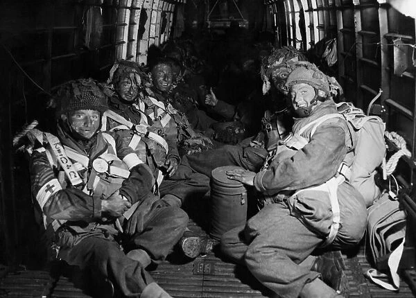 Camouflaged with blackened faces, paratroopers take up their position in their aircraft