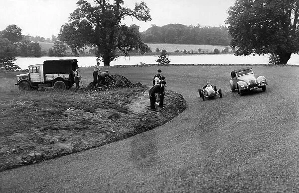 Two car drivers racing around a corner on a racetrack. July 1954 P009550