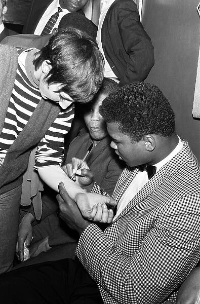 Cassius Clay aka (Muhammad Ali) signs his autograph on a fan