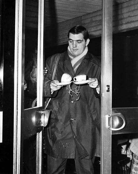 Celtic player Bobby Murdoch spilling his coffee at the airport as the team travels to