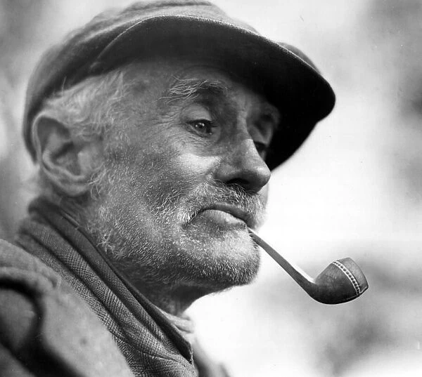 Character Studies. Old man smoking pipe wearing coth cap. P044413 Circa 1933
