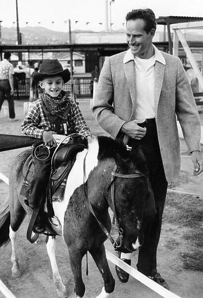 Charlton Heston with a young boy on a horse