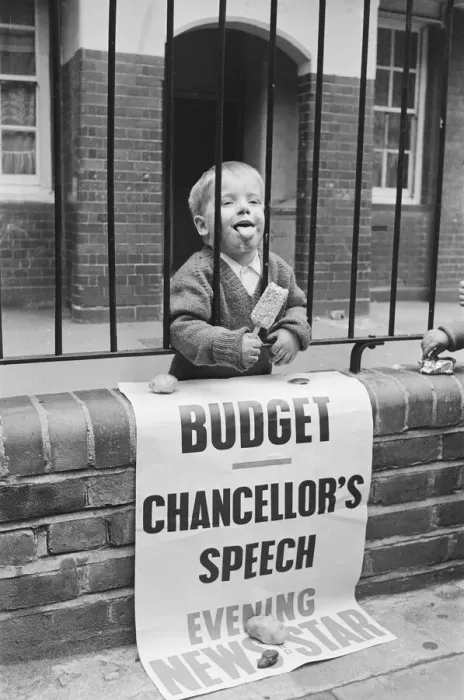Framed Print : Child eating ice cream from behind school railings on budget day Framed Print : Child eating ice cream from behind school railings on budget day