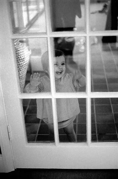 Child of Peter Shelley laughing at him through a glass door, while he plays with his dog