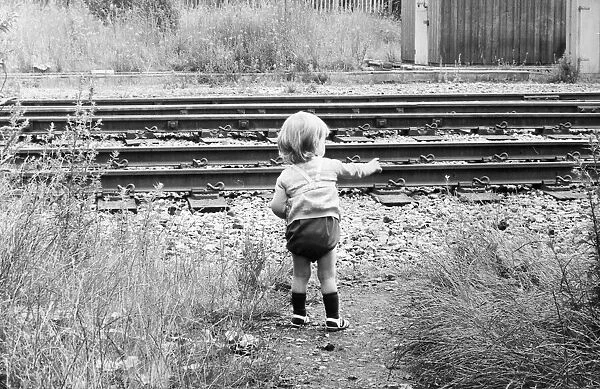 A child toddles terrifyingly close to an unprotected railway track