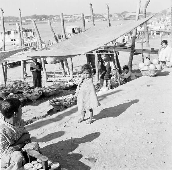 A child watches the market traders beside the harbour set up their stalls in Dacca