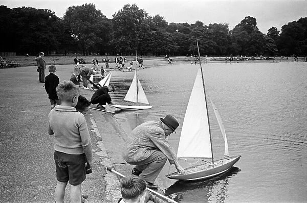 Children and adults sailing their toy yachts on the Round Pond in Kensington Gardens
