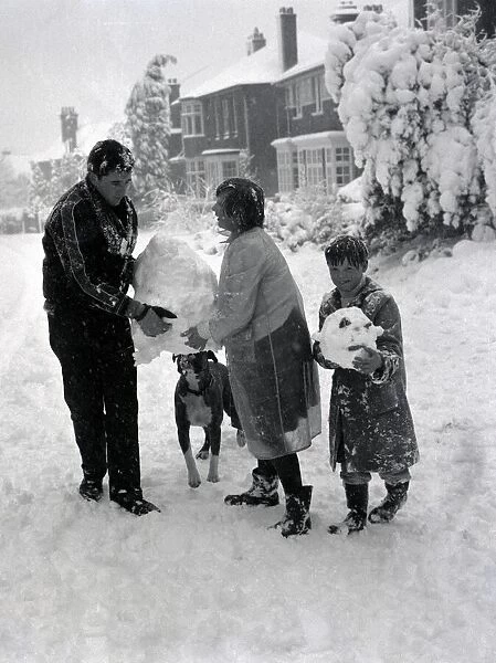 Children build a snowman with the help of their boxer dog in Hadley Wood Hertforshire