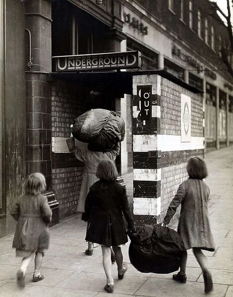 Children carrying bundles of laundry run towards the London Underground to take cover